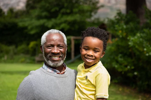 Bahçede Torunu Olan Çocuğu Taşıyan Kameraya Gülümseyen Yaşlı Afrikalı Amerikalı — Stok fotoğraf
