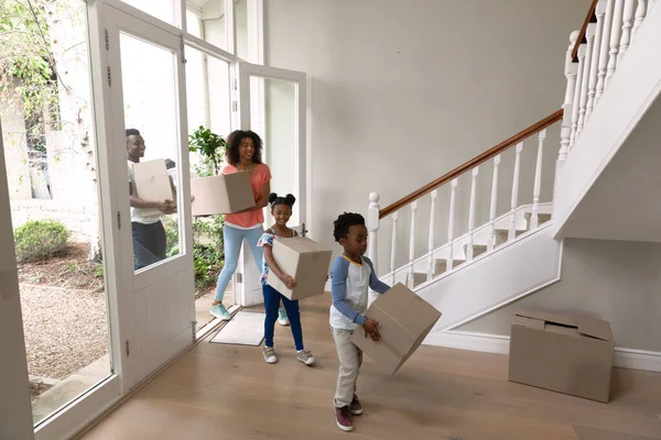 自宅で息子と娘とアフリカ系アメリカ人のカップルの正面図は 彼らの家に移動し 段ボール箱を運ぶ — ストック写真