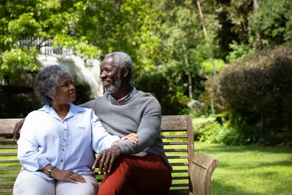 Vista Frontal Casal Afroamericano Sênior Jardim Sentado Banco Abraçando Conversando — Fotografia de Stock