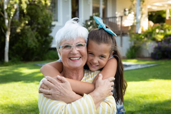 一个面带微笑的白种人祖母和孙女在花园里拥抱 并对着镜头微笑的画像 — 图库照片