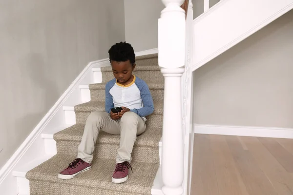 Framifrån Afroamerikansk Pojke Hemma Sitter Trappor Och Använder Smartphone — Stockfoto