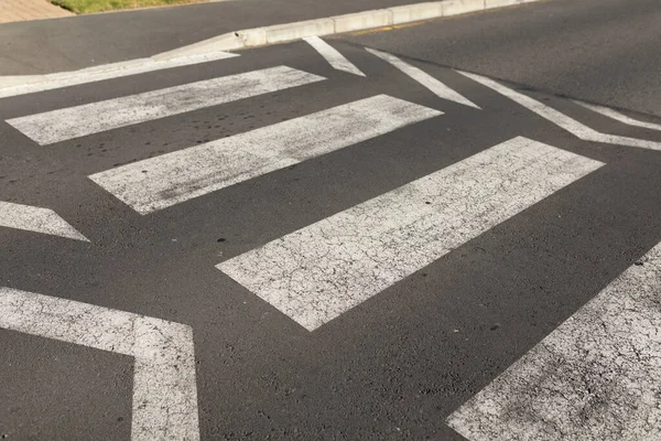 日中歩行者の交差点を示す白いマーキングと空のアスファルトの道路表面のクローズアップ — ストック写真