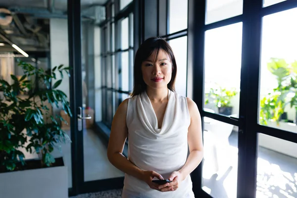 스마트 사무실에서 스마트폰을 카메라를 뚫어지게 바라보는 아시아 여성의 — 스톡 사진