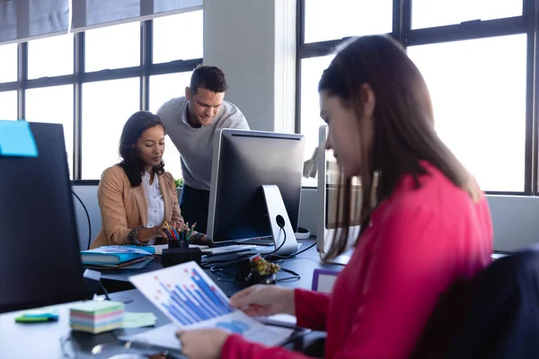 現代のオフィスで働いている白人女性の側面図を見て背景で働いている2人の同僚と — ストック写真