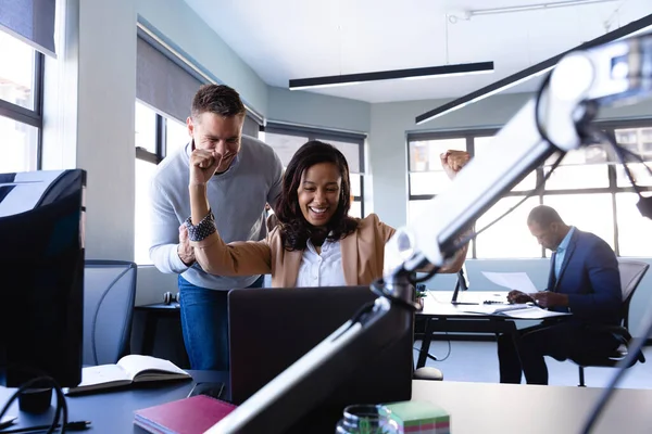 現代のオフィスで働いている白人男性がノートパソコンを見て笑顔で手を上げていました — ストック写真