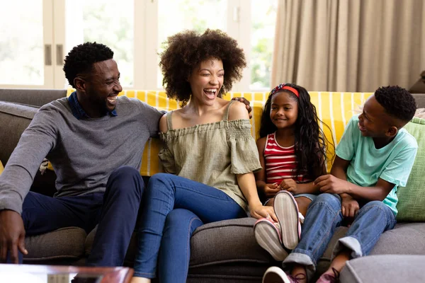 混血种族的家庭在一起享受他们在家里的时光 坐在沙发上 面带微笑地相互望着 社交上保持距离 并在禽流感流行期间自我隔离 — 图库照片