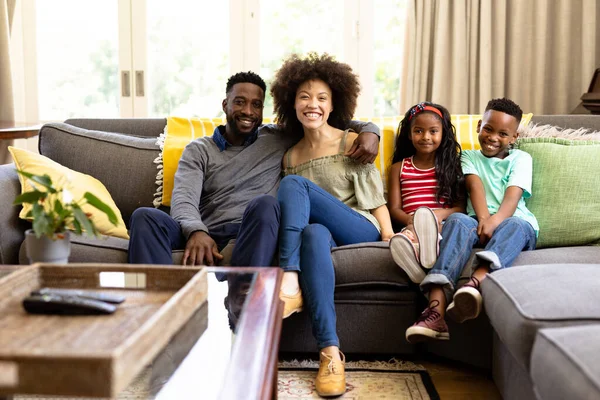 混血种族的家庭在一起享受他们在家里的时光 坐在沙发上 看着摄像机 社交上的疏远和自我隔离 这些都是在科罗纳韦病毒肆虐期间被隔离起来的 — 图库照片