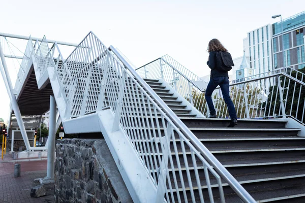昼間は街中の白人女性が リュックを背負った橋の上の階段を歩いている — ストック写真