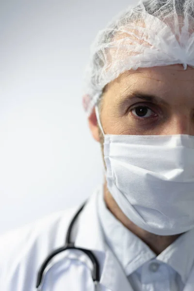 医者の制服を着た白人男性の肖像と肩の聴診器 フェイスマスクを着用し 空の白い部屋に立って カメラを見て — ストック写真
