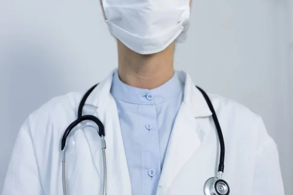 一名身穿实验室外套 戴口罩 头颈上戴听诊器 头戴眼镜片19岁的白人女性保健工作者的中间部分 — 图库照片