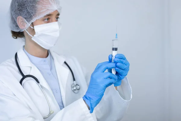 研究室のコートを着て白人女性医療従事者 コロナウイルスに対するフェイスマスクと外科手袋 Covid 注射器を保持 — ストック写真