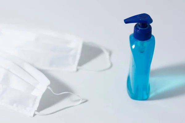 Nahaufnahme Von Zwei Weißen Gesichtsmasken Und Einer Blauen Flasche Desinfektionsmittel — Stockfoto