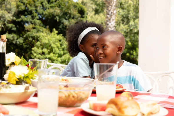 African American Girl Whispering Her Brother Ear Family Lunch Garden — Stock Photo, Image