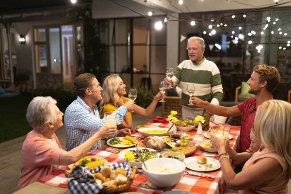 多世代の白人の家族が一緒に家で時間を楽しみ テーブルに座り 話し合い お互いを見て笑顔で乾杯しました — ストック写真