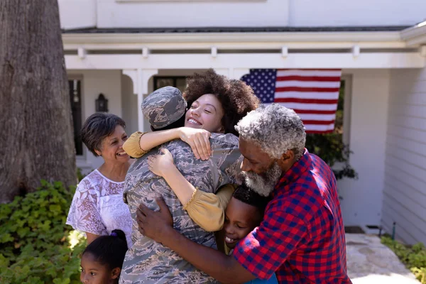 在阳光灿烂的日子里 世世代代的混血家庭在花园里度过了一段愉快的时光 欢迎一位身穿军服的非裔美国人回家 拥抱家人 — 图库照片