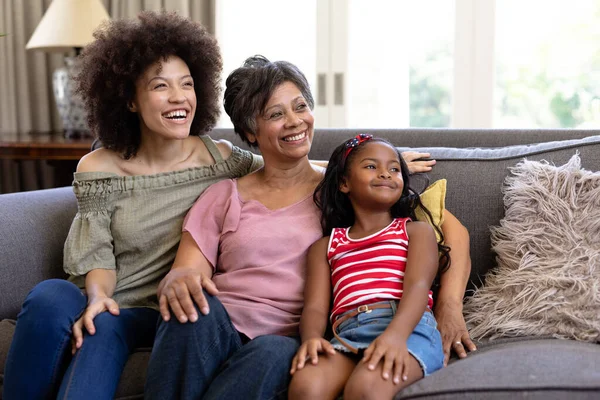 代代相传的混血家庭享受着在家里呆在一起的时光 坐在沙发上 拥抱着 微笑着 从摄像机前望去 — 图库照片