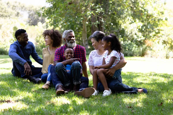 Familia Mestiza Multigeneracional Disfrutando Tiempo Jardín Sentados Hierba Abrazándose Mirándose —  Fotos de Stock