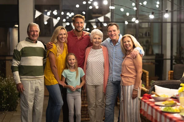 多世代の白人の家族が一緒に家で時間を楽しんで テーブルのそばに立って カメラを見て 抱きしめ — ストック写真