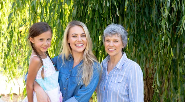 晴れた日に彼女の娘と彼女の孫娘と一緒に庭で時間を過ごすシニア白人女性 笑顔とカメラにまっすぐに見て — ストック写真