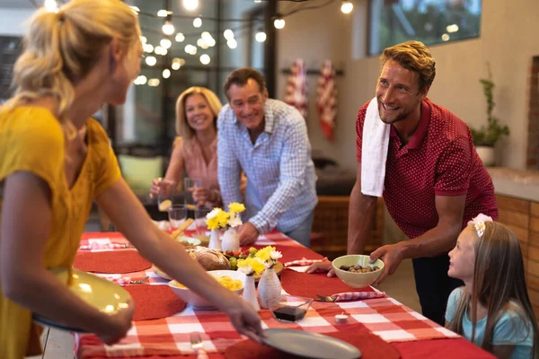 一代又一代的白人家庭在一起享受他们在家里的时光 摆设餐桌 相互凝视 交谈和微笑 — 图库照片