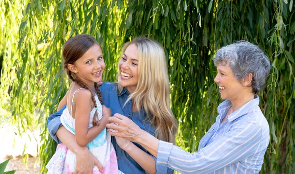 晴れた日に彼女の娘と彼女の孫娘と一緒に庭で時間を過ごすシニア白人女性 抱擁と相互作用 — ストック写真