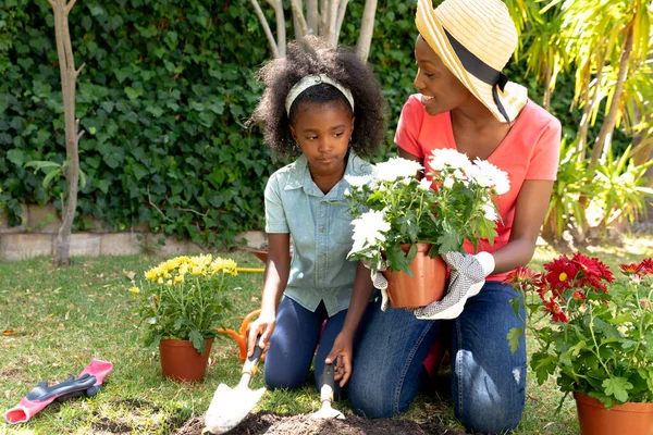 アフリカ系アメリカ人の少女と彼女の母親は庭で時間を過ごし 花を植えます 隔離された封鎖における社会的距離と自己隔離 — ストック写真