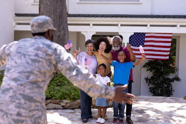 多世代混合レース家族は庭で彼らの時間を楽しんで 軍隊の制服を着たアフリカ系アメリカ人男性を歓迎し 晴れた日に家に帰る — ストック写真