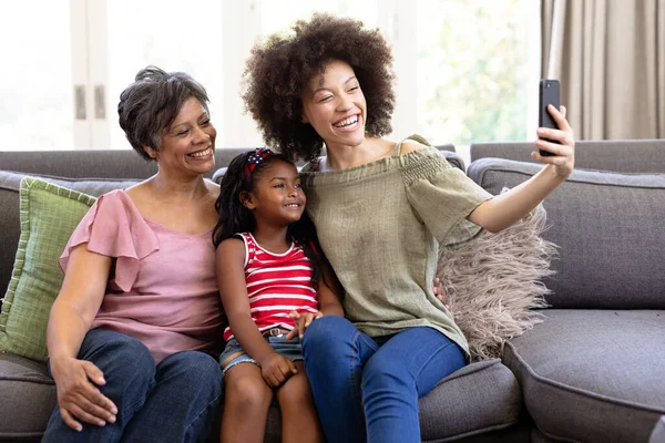 代代相传的混血家庭享受在家里呆在一起的时光 坐在沙发上 用智能手机 自私自利 — 图库照片
