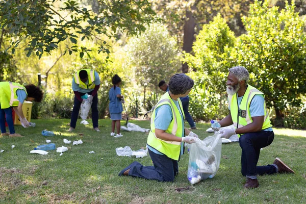 자원자 티셔츠를 바깥에서 시간을 보내며 쓰레기 봉투를 사람들에게 나누어 주었습니다 — 스톡 사진