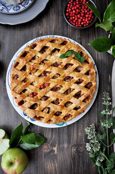 On a plate home apple pie with cranberries is decorated with mint