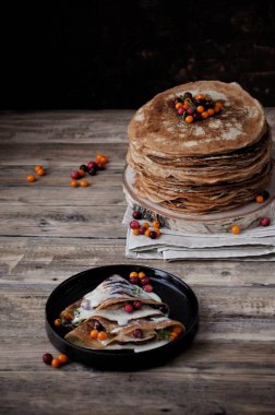 Ahşap bir masaya bir stand yoğunlaştırılmış süt ve çilek ile ince krep yığını