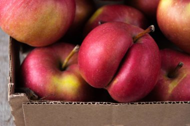 Bir karton kutu içinde ahşap arka plan üzerinde kırmızı taze elma