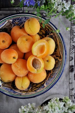 Kemikler ile taze kayısı bir tepside ahşap bir masaya çiçeklerle süslenmiş. Yukarıdan görüntülemek