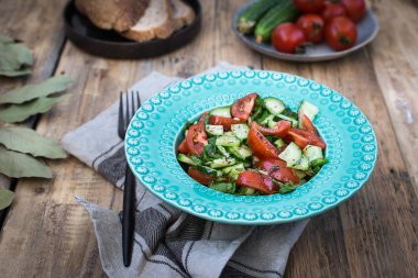 Üzerinde bir açık mavi bir salata taze salatalık ve domates ile yeşillik plaka.