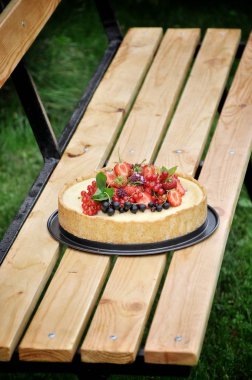 Doğa meyve pasta çilek ve diğer meyveler ile yeşil bir bahçe içinde. Bahçe bankta