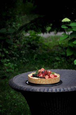 Doğa meyve pasta çilek ve diğer meyveler ile yeşil bir bahçe içinde. Dokuma masaya