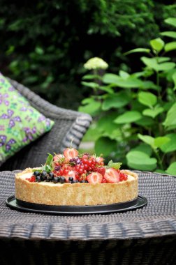 Doğa meyve pasta çilek ve diğer meyveler ile yeşil bir bahçe içinde. Dokuma masaya