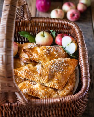 Tahta hasır sepetin içinde, elmalı, hazır poğaçalı elmalı, ev yapımı üçgen turtalar, taze elmalarla.