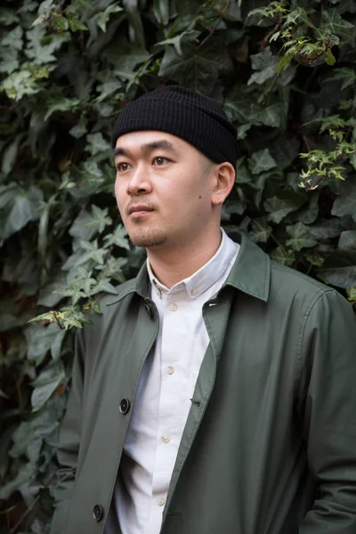Ernster asiatischer Mann vor ivi bekleidetem Hintergrund — Stockfoto