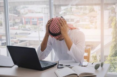 genç Arap iş adam çalışan Finans maliyeti dizüstü bilgisayar, cep telefonu ve belge üzerinde masa başında ev ofis, duygu, finans, iş teknolojisi ve yatırım kavramı hakkında vurguladı