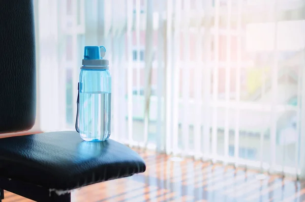 close up of blue nutrition bottle water on the sport equipment in fitness gym background, sport, fitness, healthy lifestyle and bodybuilding concept, morning sunlight effect, selective focus