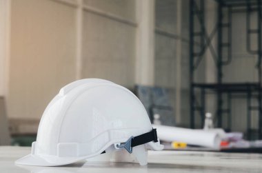 İnşaat alanında inşaat araçları ve İskele arka plan, sanayi ve inşaat kavramı ile masa üzerinde beyaz kask