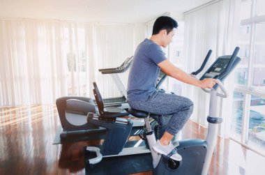 kas genç Asyalı adam onun bacakları kardiyo egzersizi bisiklet için iyi sabah, vücut geliştirme uzmanı, yaşam tarzı, sağlıklı fitness salonunda egzersiz egzersiz fitness, egzersiz ve spor eğitim kavramı