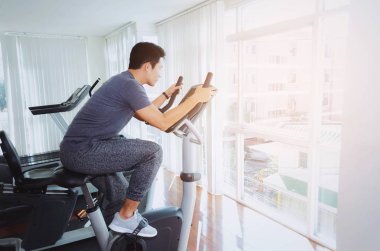 kas genç Asyalı adam onun bacakları kardiyo egzersizi bisiklet için iyi sabah, vücut geliştirme uzmanı, yaşam tarzı, sağlıklı fitness salonunda egzersiz egzersiz fitness, egzersiz ve spor eğitim kavramı