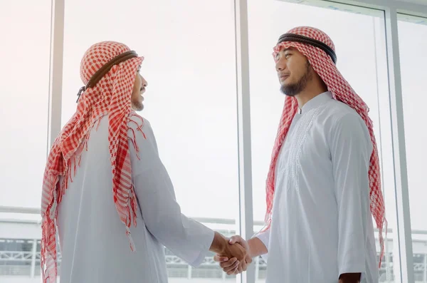 two young Arabian business man handshake after finishing up a business meeting to greeting start up project contract in office, successful, partnership, teamwork, community, connection concept