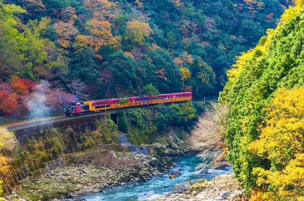 Sagano'da doğal demiryolu veya romantik tren Köprüsü ve Arashiyama, Kyoyo, Japonya nehirde tekne ile renkli sonbahar sezonu güzel dağ manzarası