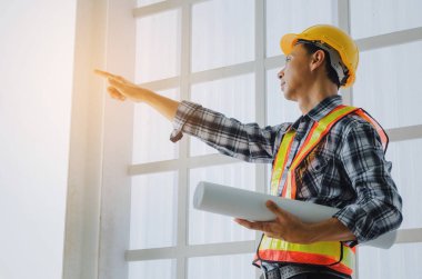 Orta yaşlı Asya mimar, mühendis veya teknisyen adam Emanet kask holding blueprint ve inşaat sitesi yapı proje, iş, sanayi kavramı tebrik başlatmak için işaret parmağı ile