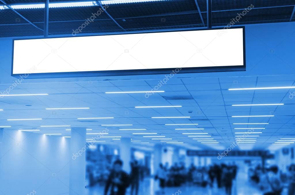 hanging advertising billboard or blank showcase light box for your text message or media content with people walking at the airport, commercial, marketing and advertisement concept, blue color tone