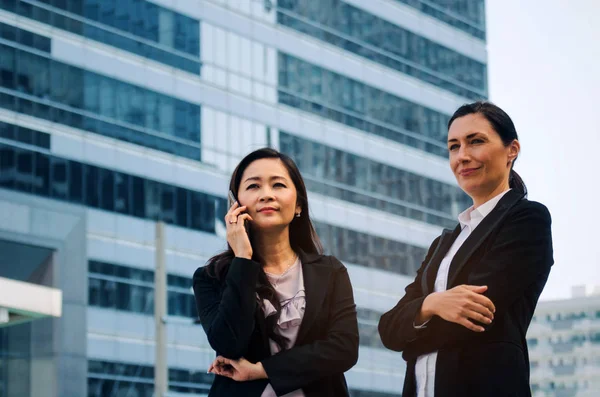 cep telefonu ve silah ile iki iş Asya ve beyaz kadın ayakta modern şehir, başarılı, destek, Toplantı, ortağı, ekip çalışması, topluluk, Internet, ağ bağlantı kavramı geçti