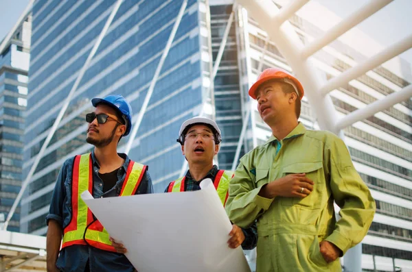 エンジニア 技術者や建築の近代的な都市の建物の背景 建設現場 ビジネス および労働者の概念設計と計画に関する計画安全ヘルメットと建築家のグループ — ストック写真